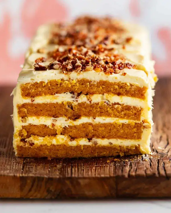 Un pastel de calabaza enorme con capas, nueces pecanas caramelizadas y glaseado de queso crema