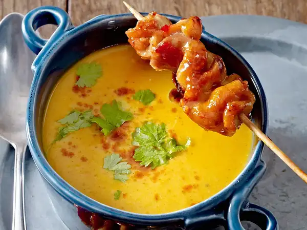 Oven-baked pumpkin and coconut soup with chicken skewers