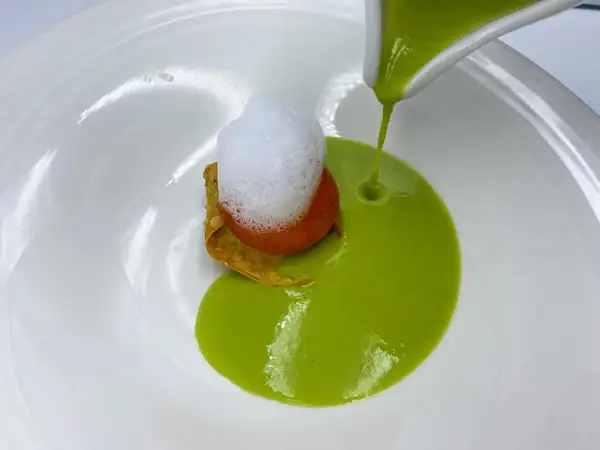 Black sausage and cured egg yolk ravioli with pea cream and anise foam