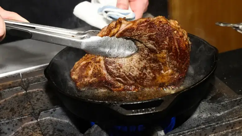Turning the ribeye steak over frequently results in a crispy crust and a uniform pink center.