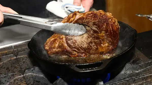 Turning the ribeye steak over frequently results in a crispy crust and a uniform pink center.