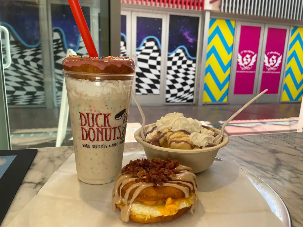 Duck Donuts llega al Strip con cordones para el cuello con forma de batido alcohólico de un metro veinte de altura