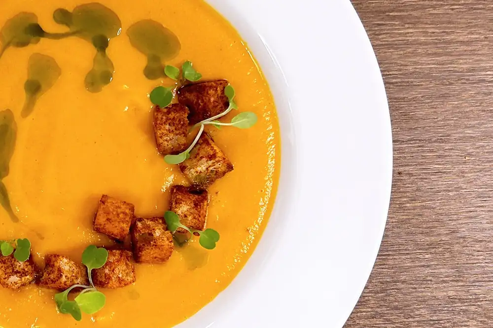 Sopa de tomate ahumado con picatostes de tomate y aceite de albahaca de Refettorio Harlem