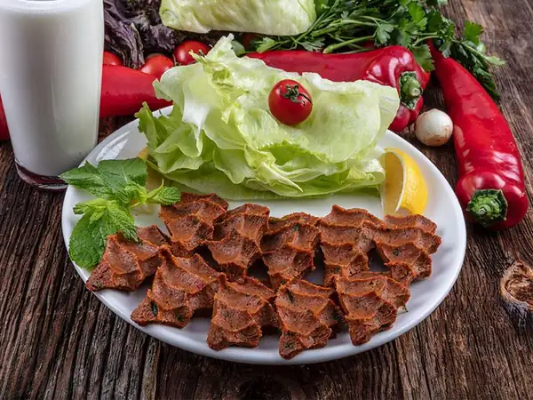 What gives raw meatballs (çiğ köfte) their dark color?