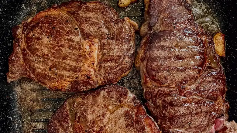 Cooking too many steaks at once cools the pan and cooks the meat.